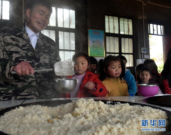 张玉滚在为学生们盛午饭（3月20日摄）。新华社记者 李嘉南 摄